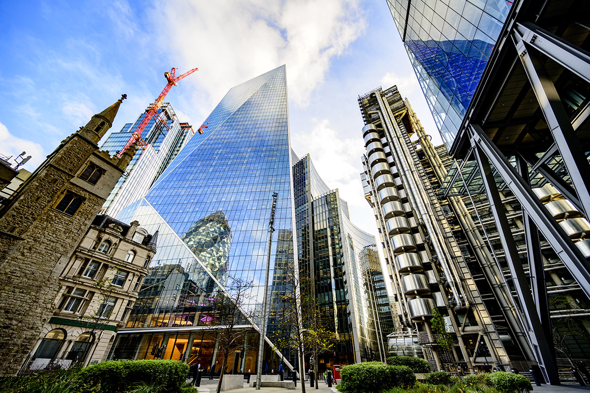 Low angle view of financial district building exteriors with mixed architecture and construction crane on site of new development.